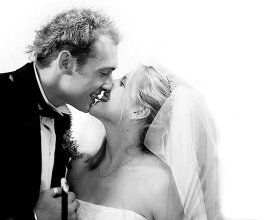 black & white photo of bride and groom sharing real chocolate wedding cake.