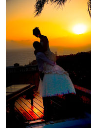 Romantic sunset wedding - Groom is lifting up bride.