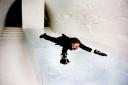 Groom in his wedding suit sliding on ice sculpure in Ice Hotel bedroom