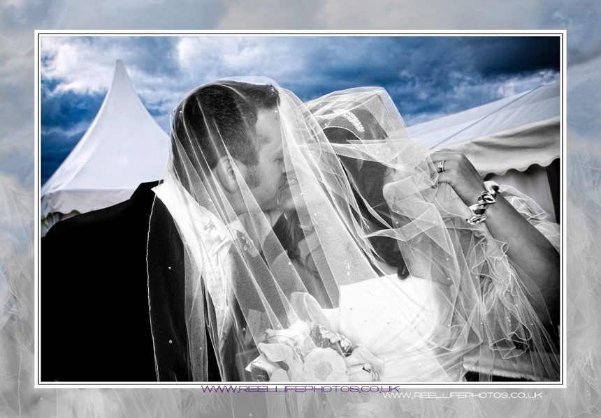 black and wedding photo of bride and groom kissing at farm wedding