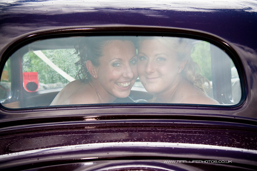 all female gay couple looking through wedding car back window 