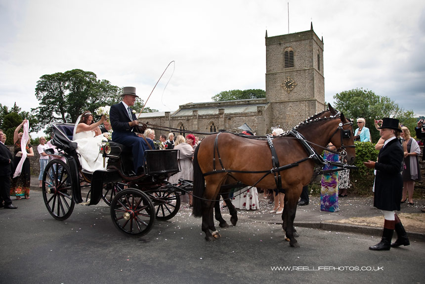 bride and groom leave Wesnley Church in a horse and carriage