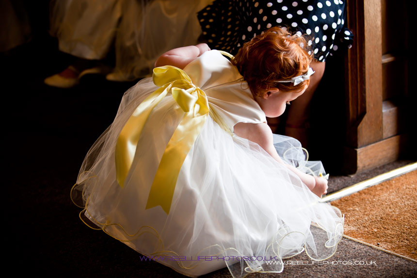 baby flower girl plays with petals by St Mary's Church door