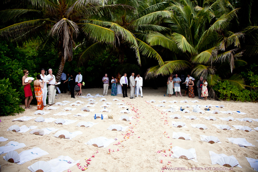 guests in the shade of palm trees before beach wedding in the Seychelles