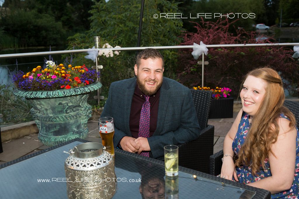 Happy evening wedding reception guests at Waterton Park Hotel outside of the island patio which is decorated with flowers
