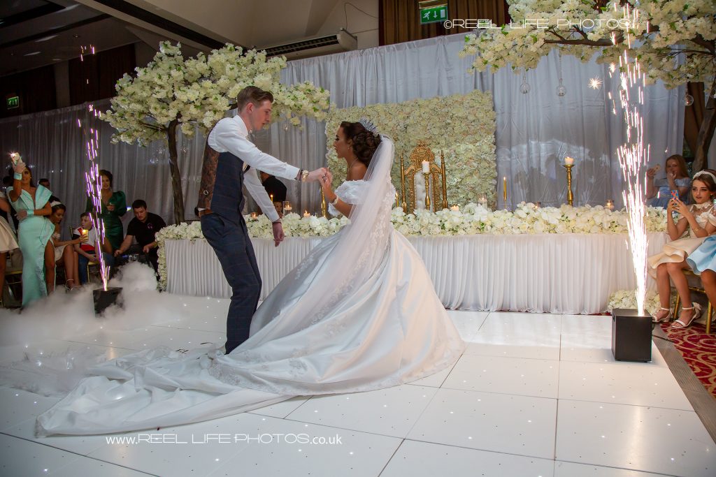 Traveller groom treads on bride's  wedding dress during their first dance with indoor fireworks at Cedar Court Hotel in Bradford
